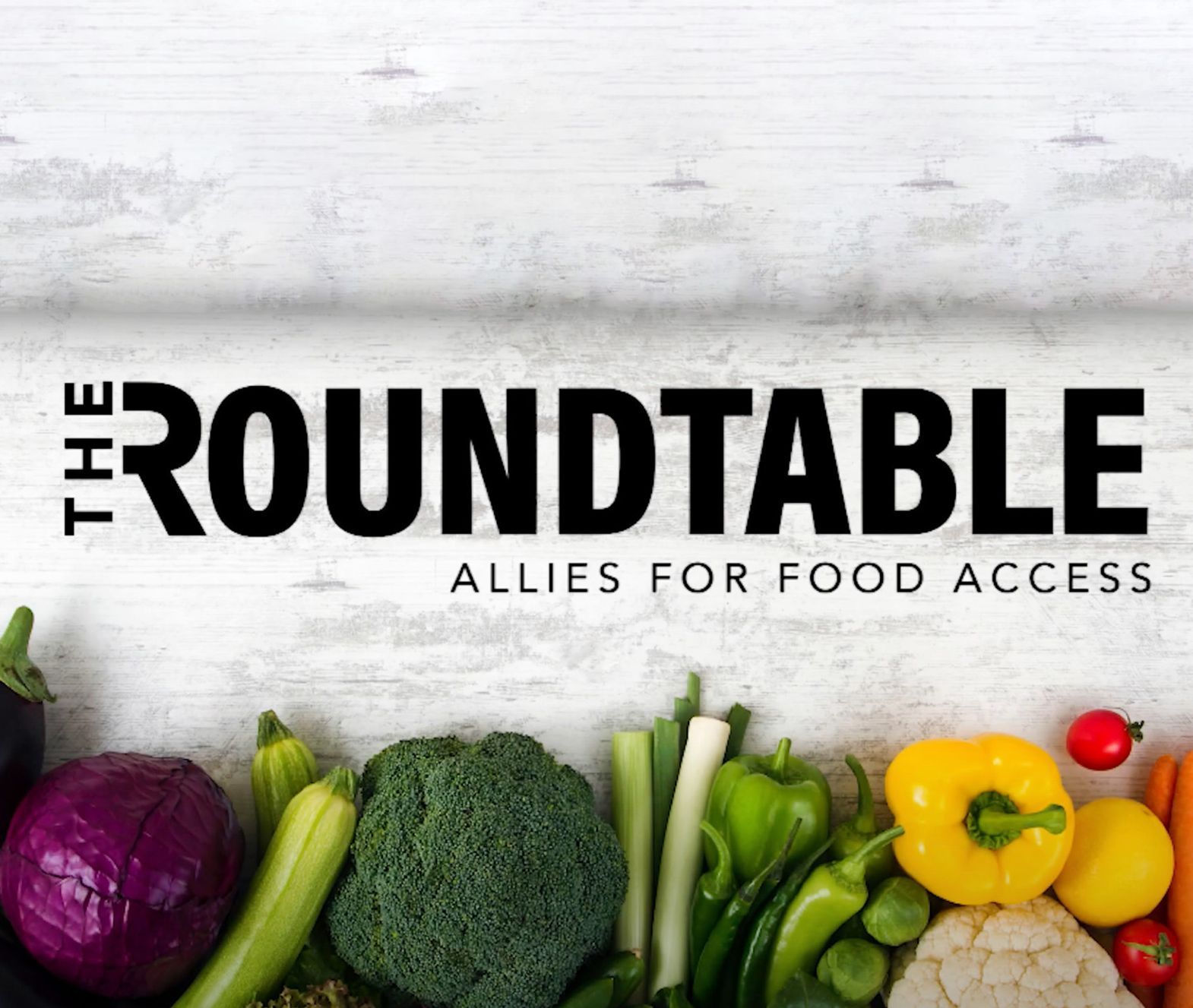 The logo for "The Roundtable" has the words "Allies for Food Access" underneath its name. It hovers over a line of colorful vegetables including red cabbage, brocolli, and tomatoes.