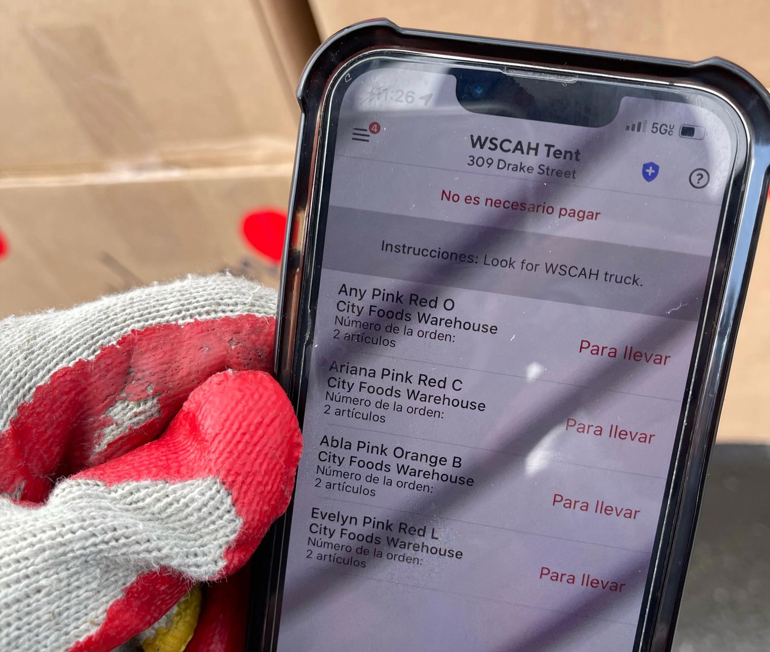 A bicyclist holding an iPhone showing the WSCAH delivery app