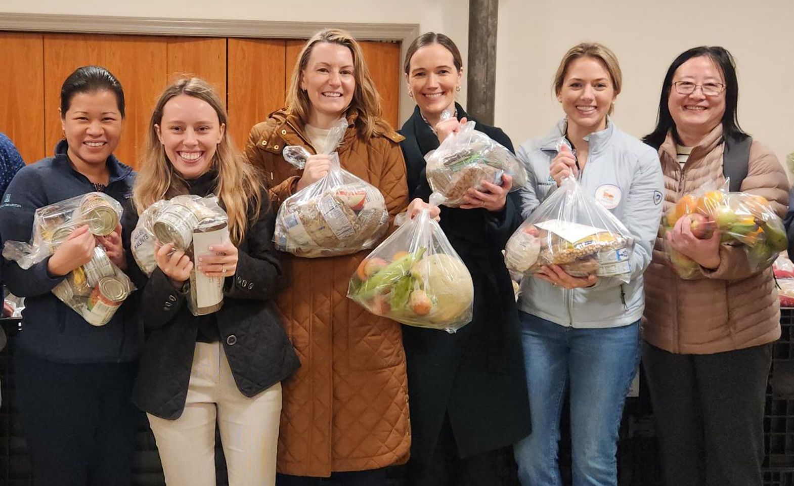 Group of people holding bags of groceries