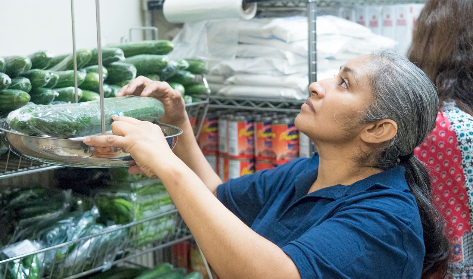 A woman in a storage room weighs cucumbers,
