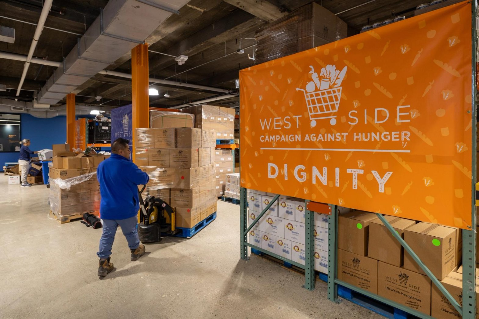 A WSCAH worker pushes a dolly stacked with food boxes through the WSCAH warehouse.