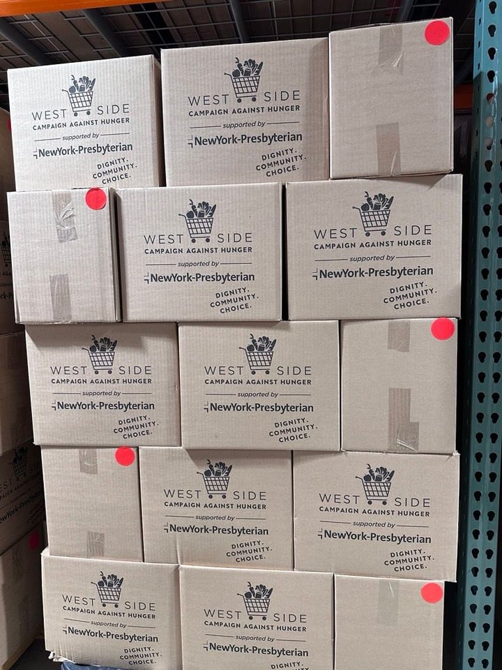 Large, white boxes are stacked in a metal shelf in WSCAH's warehouse. They have WSCAH's logo printed on them.