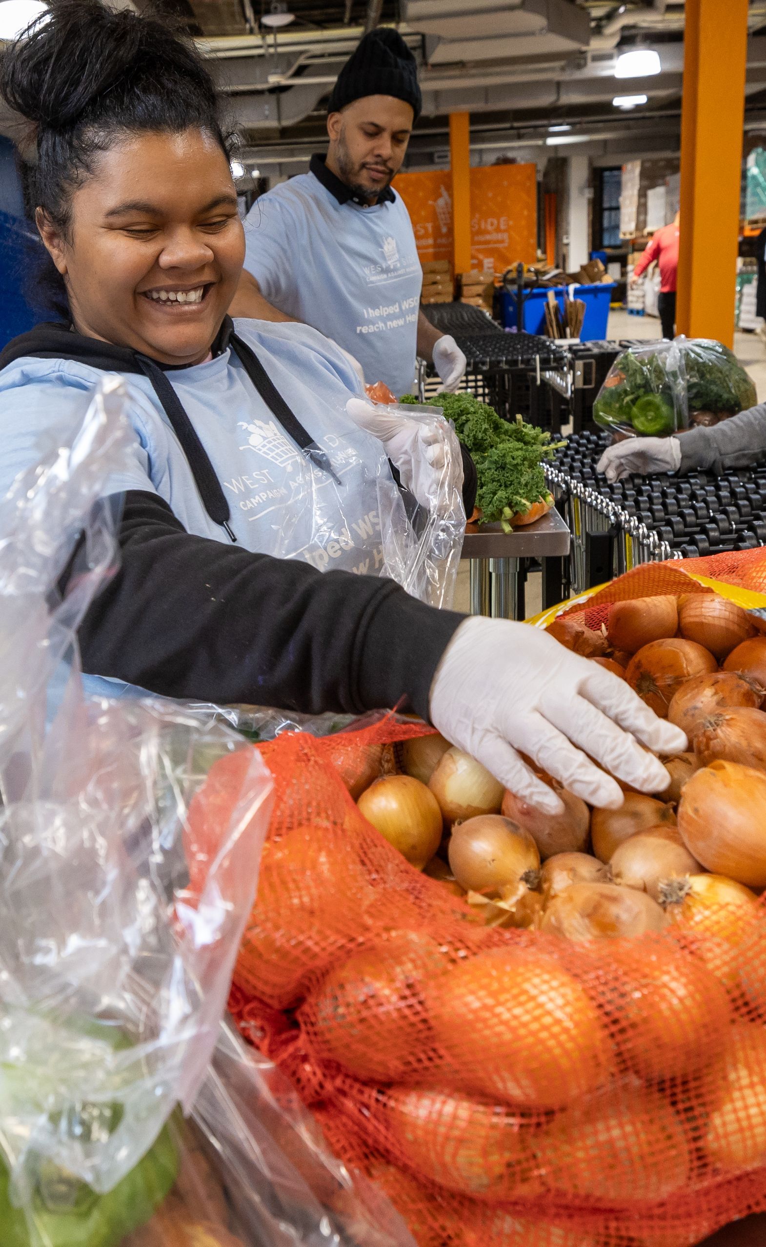 Two WSCAH volunteers sort through a package of onions in our warehouse